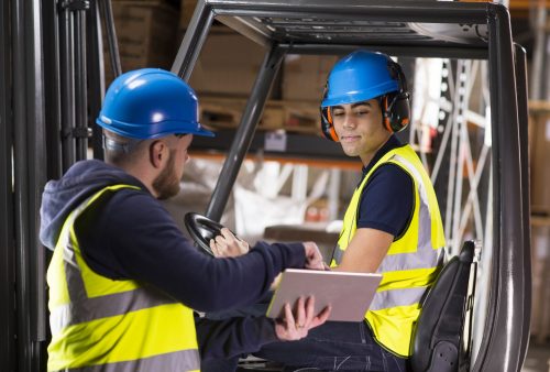warehouse supervisor chats to young forklift truck driver trainee